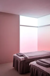 A minimalist bedroom featuring purple fabric beds under a frosted glass window.