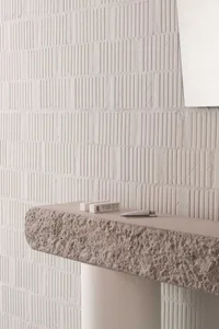 A modern minimalist interior with a textured concrete ledge against a white textured wall.