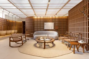 A minimalist modern lounge area with wooden furniture and cloth upholstery, featuring a round coffee table, white sofa, and l