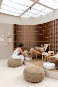 A minimalist spa interior features natural fiber poufs and wooden louvers.