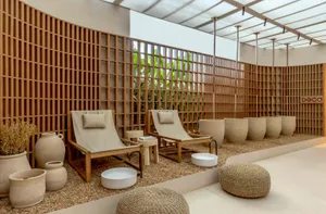 Minimalist spa relaxation room with concrete and wood elements, featuring comfortable seating and plants.