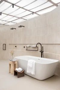 A modern bathroom featuring ceramic tiles, an oval-shaped bathtub, and multiple shower heads.