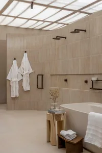 Modern bathroom with concrete tiles, white robes, and a freestanding tub.