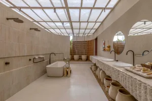 A modern bathroom featuring concrete tiles, a freestanding bathtub, and potted plants lined along the walls.