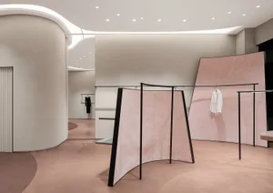 Modern minimalist fashion retail store with pink ceramic powder flooring and pink curtains.