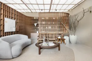 Modern living room featuring a curved sofa, round table, and wooden panels on the walls and ceiling.