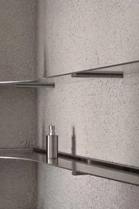 Modern metal shelves with glass surfaces against a textured wall.