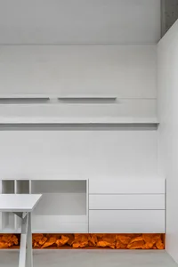 A minimalist office space featuring white concrete walls and shelves.