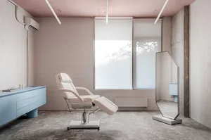A sleek, minimalist medical office featuring a white leather reclining chair and a large floor-to-ceiling window.