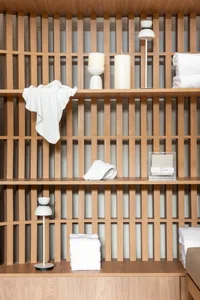 A minimalist shelf made of wood, featuring white towels and candles.