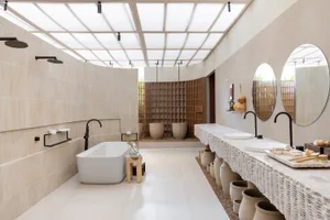Modern minimalist bathroom featuring stone tiles, a freestanding bathtub, and a double sink vanity.