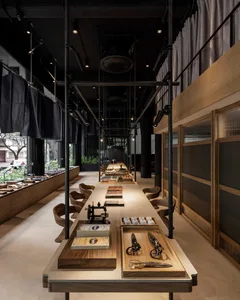 Modern retail space featuring a long wooden table with various items and seating arrangements in a dark, industrial-style set