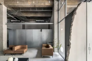 Industrial modern office interior with concrete, metal, and leather furniture.
