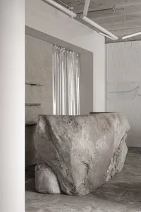 A modern office with a large, roughly-sculpted concrete reception counter.