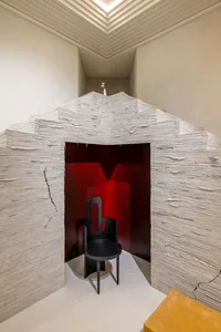A minimalist architectural interior with textured plaster walls and a red-lit niche.