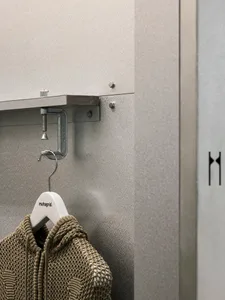 Clothing hooks hanging on a metal shelf in a storage area.