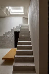 A modern staircase with concrete steps and a textured wall in an indoor setting.