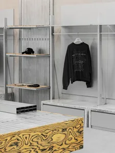 A minimalist clothing retail display featuring industrial-style metal shelves and marble countertops.