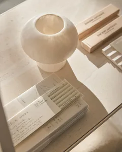 Minimalist desk accessories including pencils, stationary, and a vase on a light-colored tabletop.