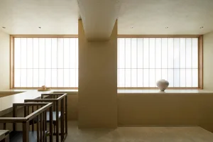A minimalist interior design featuring a window with white panels and a wooden vase on a ledge.