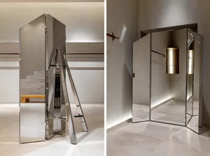 A modern closet made of aluminum with folded metallic surfaces and a minimalist design, featuring a hanging rod and a mirror.