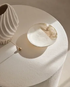 A modern, minimalist ceramic plate with intricate designs placed on a textured white surface.