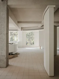 A modern living room with concrete walls and white tiled flooring.