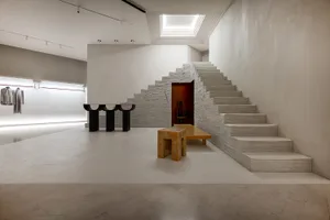 Modern retail showroom interior with concrete staircase and minimalist design.