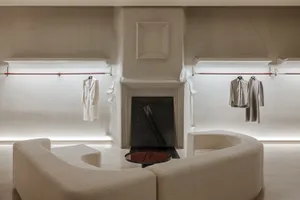 A minimalist retail store featuring a concrete interior with modern furniture and minimalist clothing hanging on the walls.