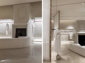 A modern retail store featuring minimalist decor with white marble cladding and minimalist dress forms.