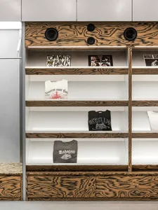 Modern retail storefront with mid-century modern wood shelves, displaying music albums, clothing, and accessories.