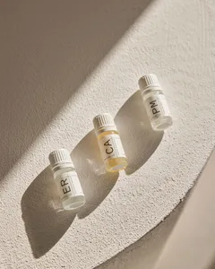 Three small glass bottles of essential oils with minimalist labels on a textured surface.