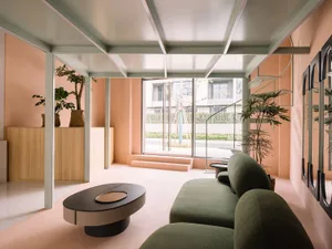 A modern minimalist living room with concrete floors, wood furniture, and green plants