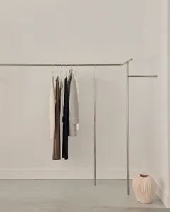 Minimalist clothing rack with metal rods and clothes hanging on it.