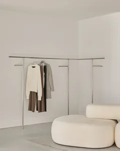 A minimalist clothing rack with white metal poles and black fabric hanging on it.