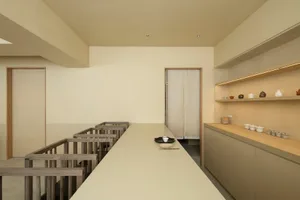 A modern interior design featuring a concrete floor with a long dining table set with minimalist ceramic dishes and utensils,