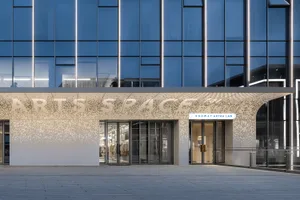 Modern shopfront with concrete and glass materials, featuring illuminated lighting.