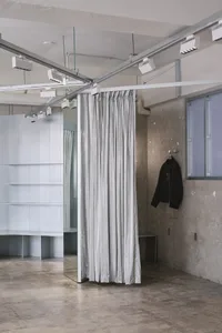 一間設有金屬陳列板、懸掛布簾，以及牆上掛著黑色外套的零售店。