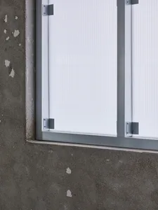 A close-up of a modern metal and plastic framed window with a white translucent shade.