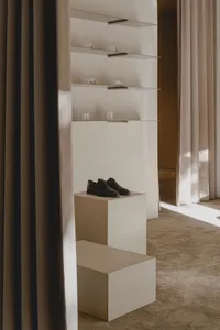 Modern retail store interior with minimalist design, featuring a concrete pedestal displaying a pair of black shoes.