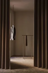A minimalist clothing display featuring a metallic stand and a suit jacket hanging from a rod.