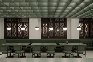 Industrial-style restaurant interior with green leather seating and white pendant lights.