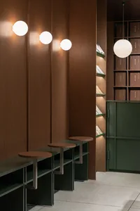 Modern minimalist library with wooden walls and metal tables, featuring spherical lighting fixtures.