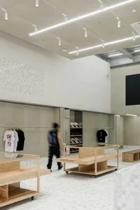 A minimalist retail shop featuring wooden furniture with white marble flooring and white walls.