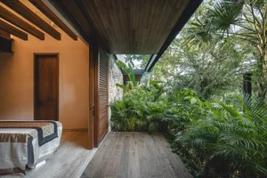 A modern bedroom with wooden walls, hardwood floors, and lush green plants.