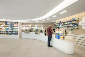 現代簡約藥局室內，配有白色曲線櫃檯與大面積商品陳列架。