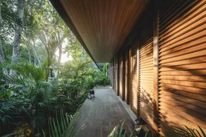 A modern house exterior with tall wooden shutters and lush greenery in the background.