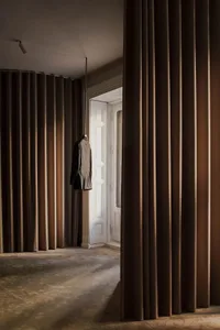 Modern interior space featuring a hanging suede jacket on a white door with high curtains.