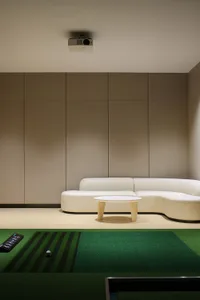 A modern interior living room with a white sectional couch, a round wooden table, and a projector hanging from the ceiling.