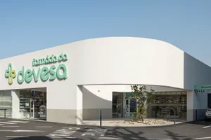 Modern pharmacy storefront with white concrete exterior and green signage